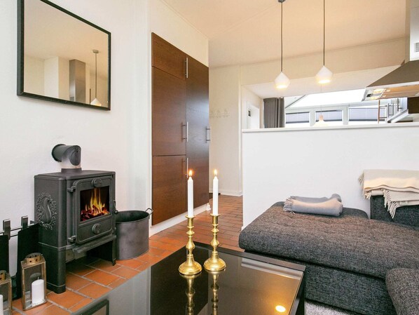 A modern living room with a fireplace, a sofa, and a table with candles. - 5 Person Holiday Home on a Holiday Park in Lemvig (Lemvig)