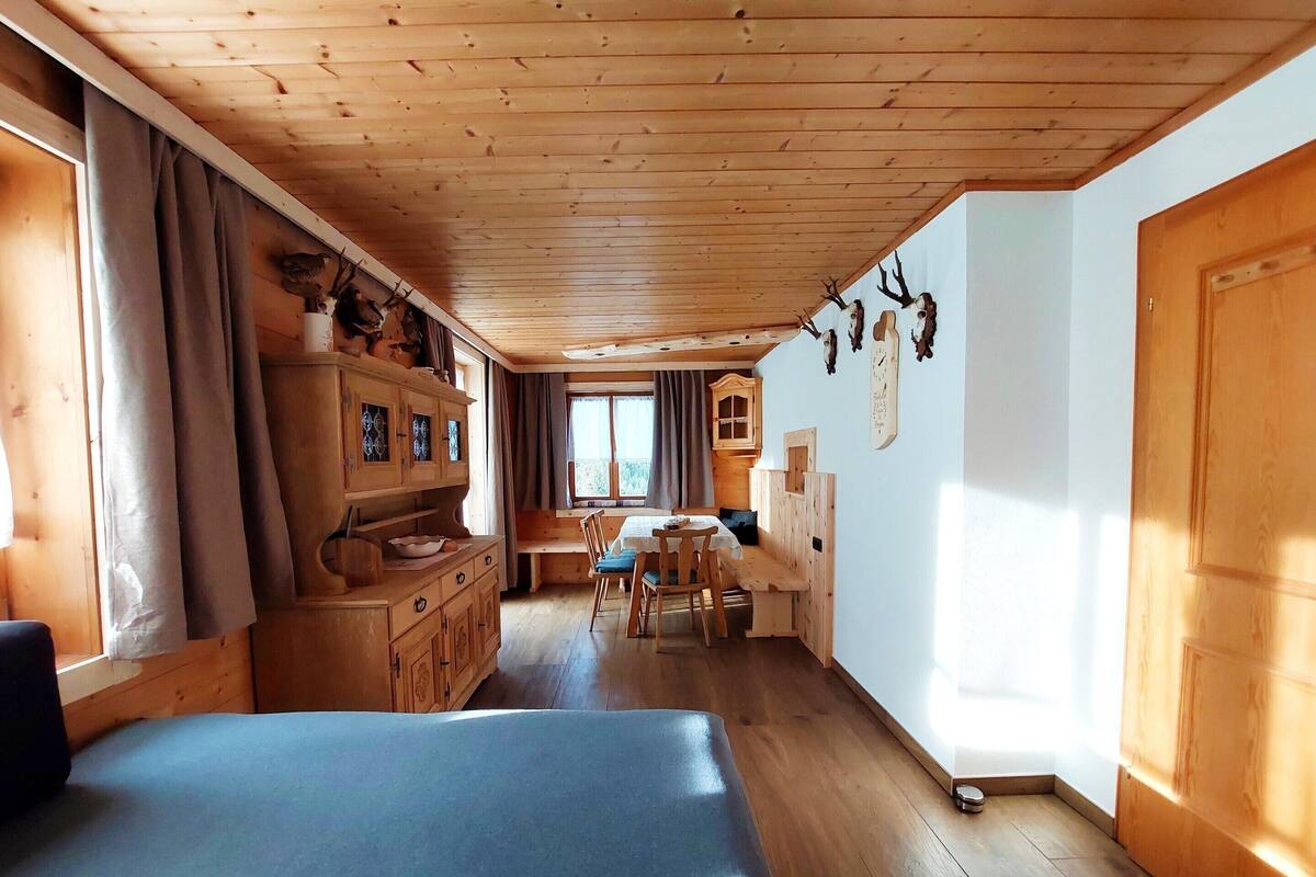 Ein Holzblockhaus mit Bett, Esstisch und Küchenzeile.