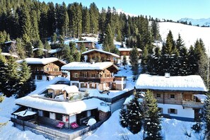 A snow-covered mountain lodge with multiple wooden buildings, surrounded by trees and a snowy landscape. - Apartment in Hochfugen With a Terrace (Fuegenberg)