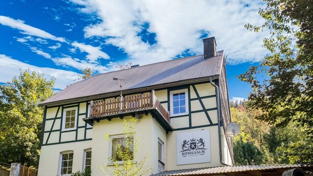 Un edificio tradicional de entramado de madera con un letrero que dice "Königsalm".