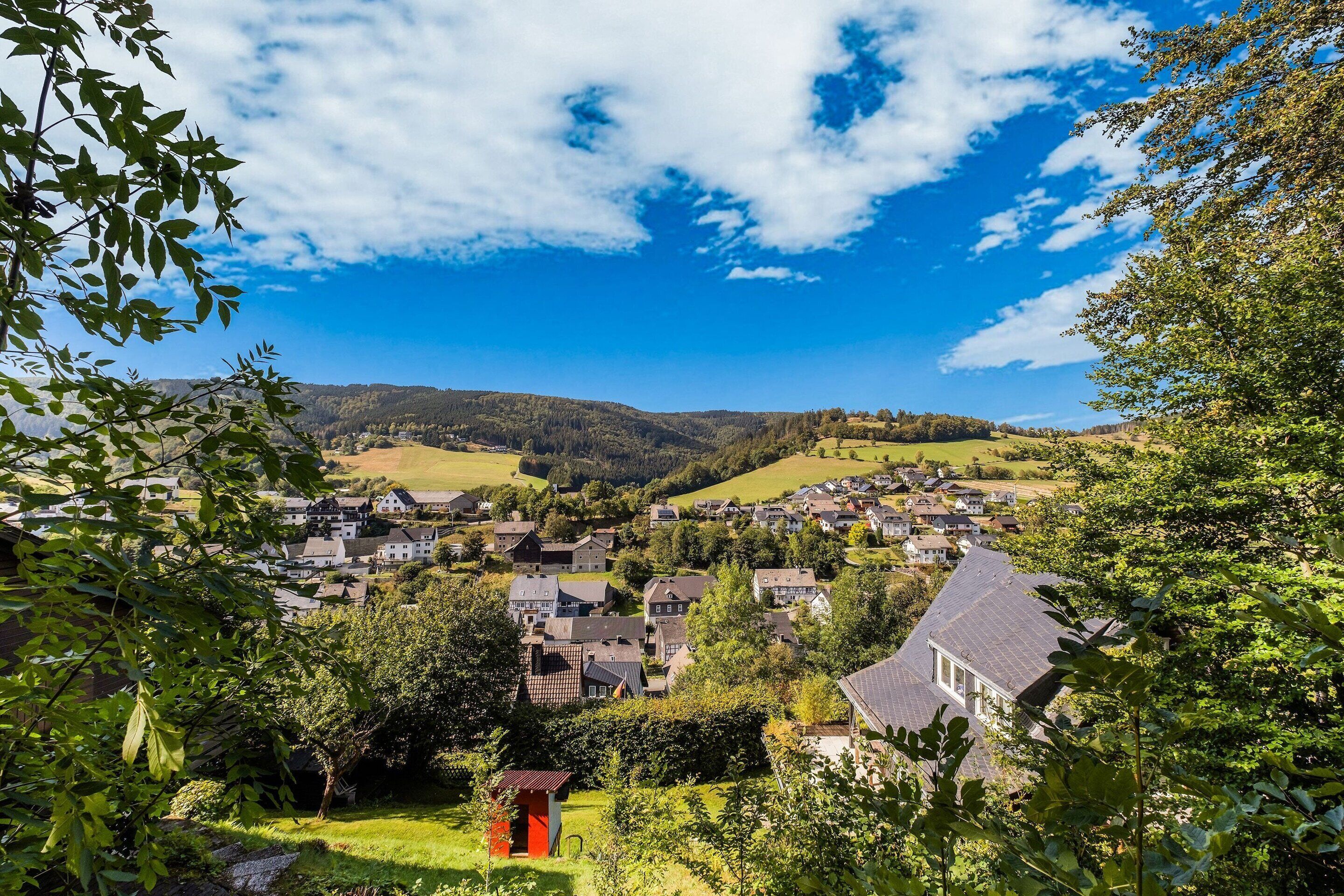 A residential area with houses, greenery, and a clear sky.