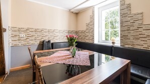 Un área de comedor con una mesa de vidrio, asientos acolchados y una pared decorativa de piedra.