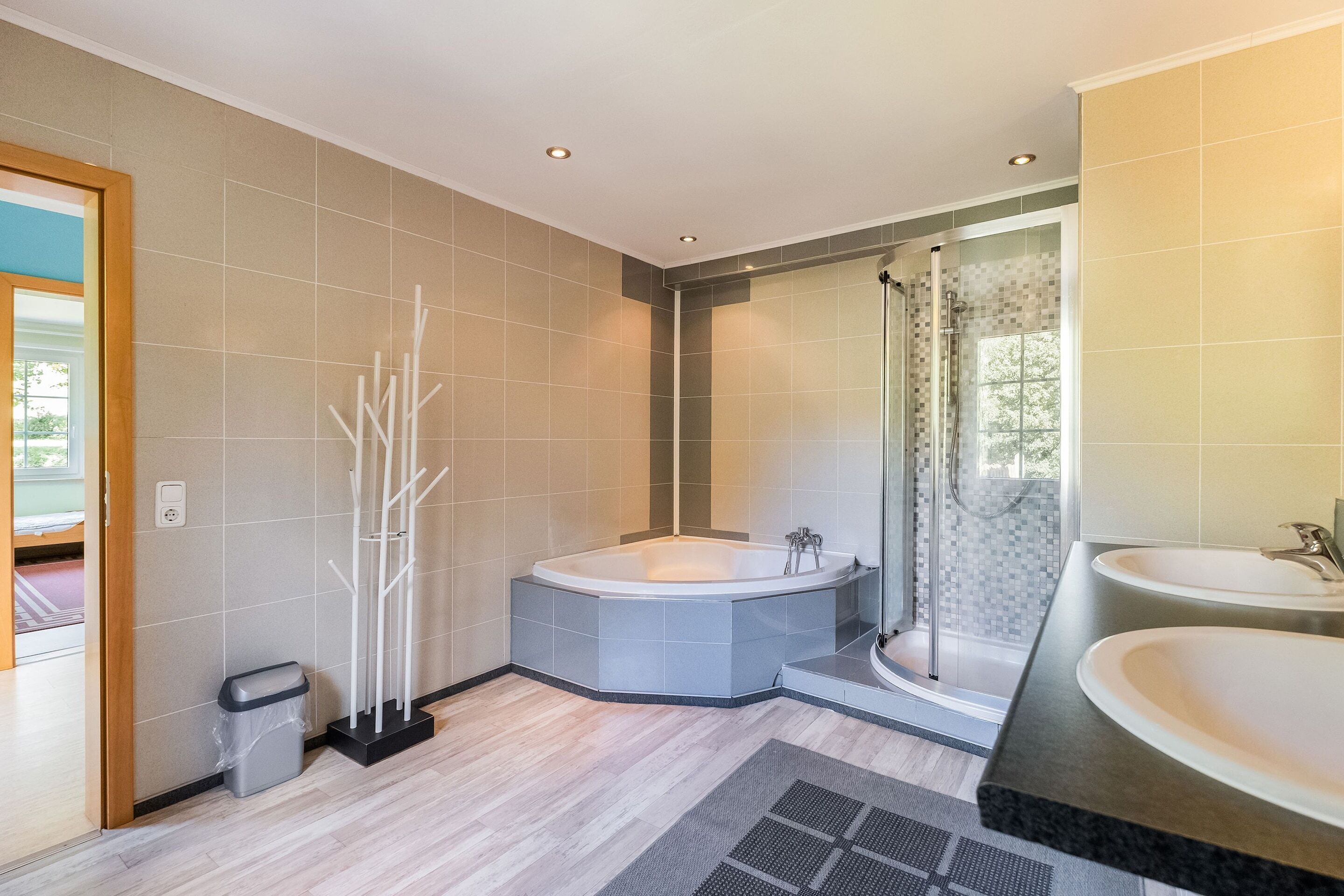 Ein modernes Badezimmer mit einer großen Badewanne, einer separaten Duschkabine und einem Doppelwaschbecken.