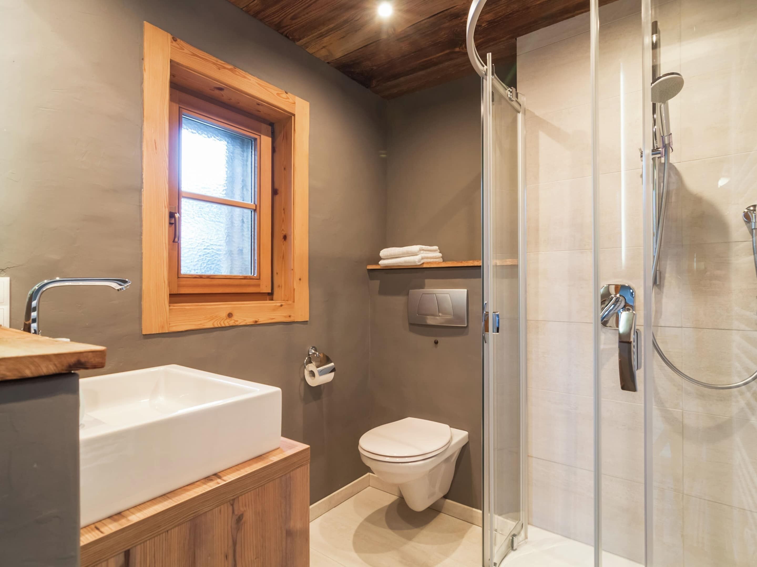 Et moderne badeværelse med et fristående badekar, toilet og en bruseområde med glasvægge.
