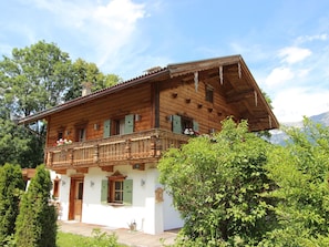 Eine Holzhütte mit Balkon, grünen Fensterläden und einer weißen Fassade.