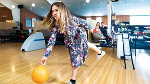 Une salle de bowling avec un plancher en bois et une personne qui joue au bowling.