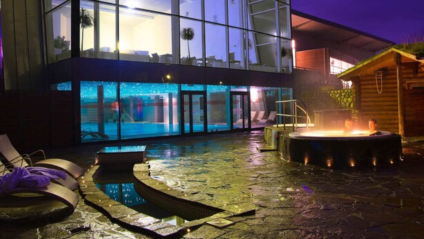 Un edificio moderno con amplios ventanales de vidrio, piscina y zona de hidromasaje.