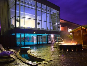 Un bâtiment moderne doté de grandes fenêtres en verre, d’une piscine et d’un espace équipé d’un jacuzzi.
