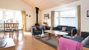 Amplia sala de estar con techo de madera, chimenea, sofá, mesa de centro y televisor.