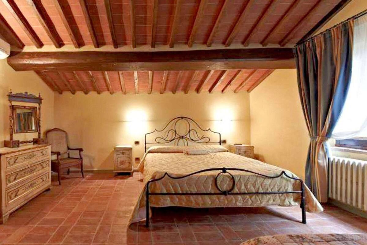 A bedroom with a bed, dresser, chair, and a window with curtains.