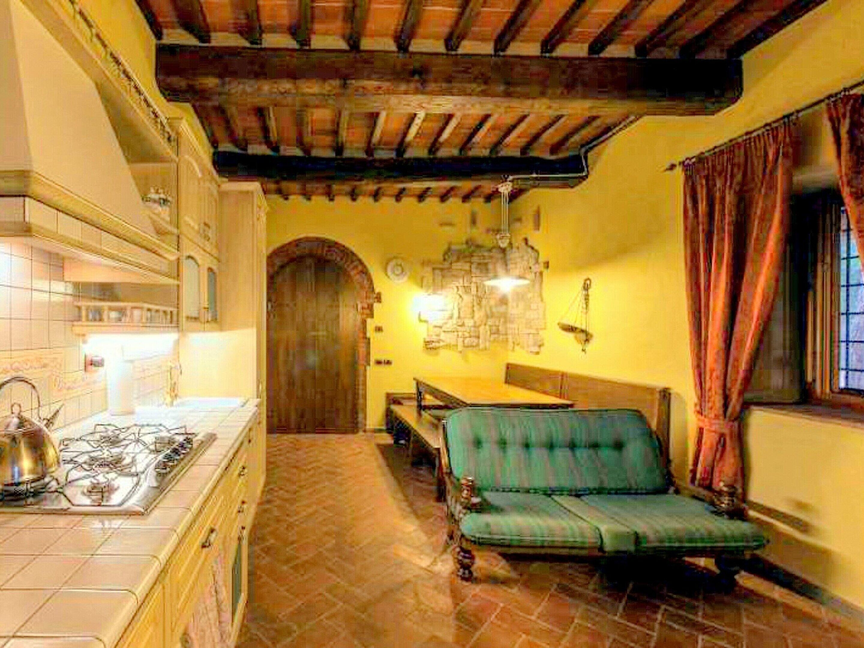Una habitación acogedora con piso de baldosas, techo de madera, una mesa de comedor con sillas y un sofá.