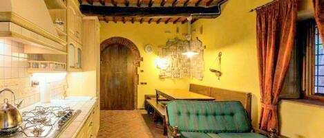 Una habitación acogedora con piso de baldosas, techo de madera, una mesa de comedor con sillas y un sofá.