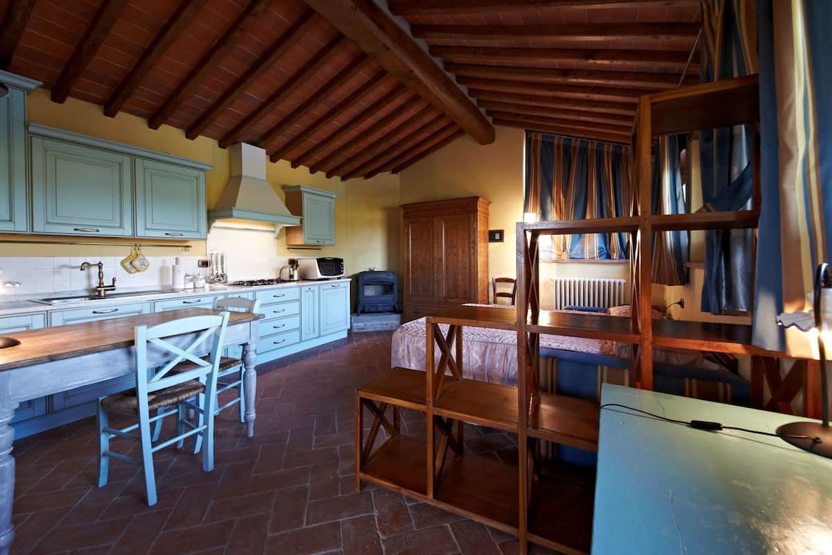 A rustic kitchen with wooden beams, a stove, and a dining area with a bench.