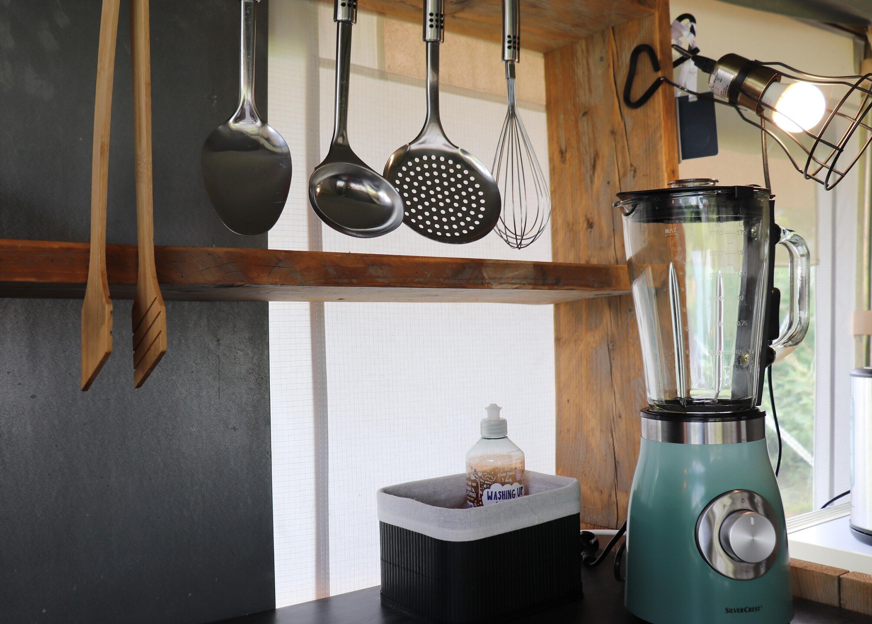 A kitchen with a blender, wooden utensils, and a bottle labeled "Washing Up".