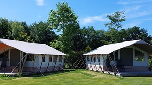 Two white tents with a triangular roof, set on a grassy field with trees in the background. - Safari Tent in the Middle of the Fryske Walden (Twijzel)