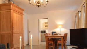 A living room with a wooden cabinet, a dining table with chairs, a TV, and a candle on a table. - A Modern Holiday Home by the River Mosel (Moselkern)