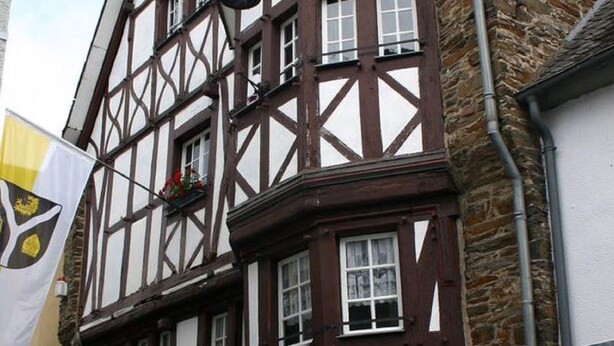A traditional half-timbered building with multiple windows and a flag. - A Modern Holiday Home by the River Mosel (Moselkern)