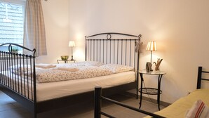 A bedroom with a metal bed frame, a bedside table with a lamp, and a window with curtains. - A Modern Holiday Home by the River Mosel (Moselkern)