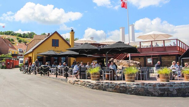 Un restaurante con terraza, paredes de piedra y una bandera.