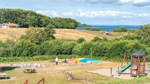 Un parque con mesas de picnic, un área de juegos y vistas al mar.