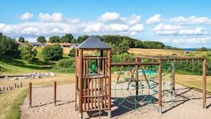 Un parque infantil con una estructura para escalar y un pequeño pabellón.