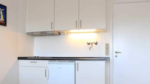 A compact kitchen with white cabinets, a built-in dishwasher, and a small refrigerator. - 2 Person Holiday Home in Aakirkeby (Akirkeby)