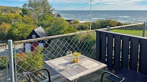 A wooden deck with a table and chairs overlooking the ocean. - 2 Person Holiday Home in Aakirkeby (Akirkeby)