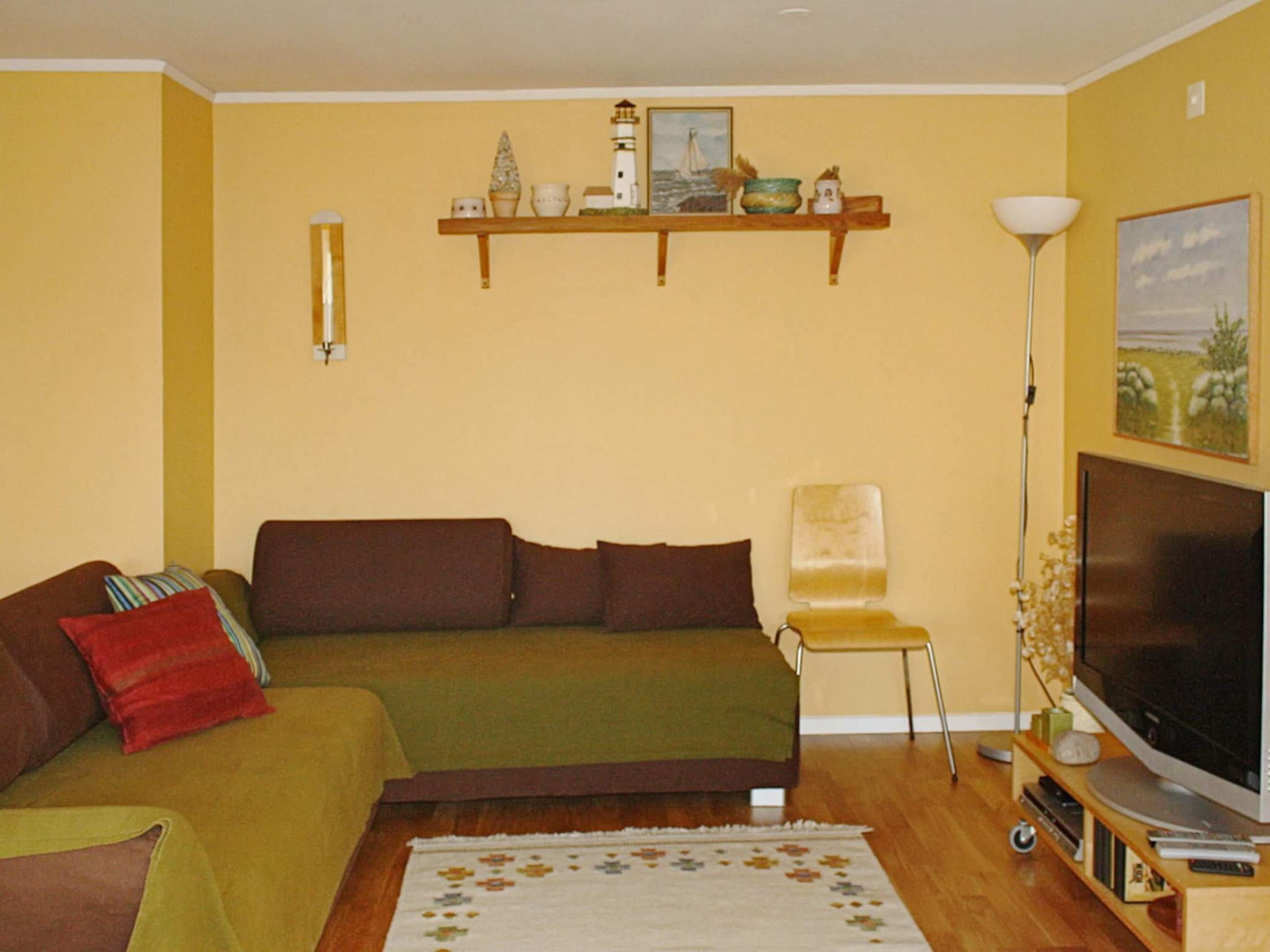 A living room with a sofa, a chair, a TV, and a lamp.