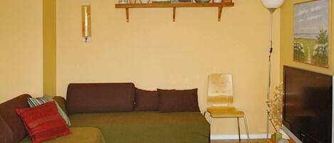 A living room with a sofa, a chair, a TV, and a lamp.