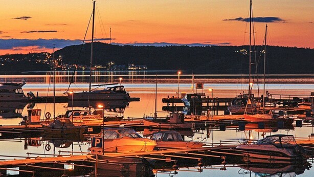 A marina at sunset with boats docked and a hill in the background. - 4 Person Holiday Home in Ellos (Ellos)
