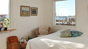 A bedroom with a large bed, a view of a harbor, and a window with a view of buildings. - 4 Person Holiday Home in Ellos (Ellos)
