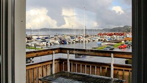 A marina with boats docked, a wooden deck, and a view of the water and distant hills. - 4 Person Holiday Home in Ellos (Ellos)