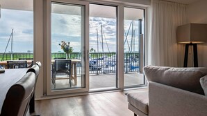 A modern room with a large sliding glass door leading to a balcony with a view of boats and a marina. - Luxury Apartment in Residence Marina Kamperland - pet Friendly (Kamperland)
