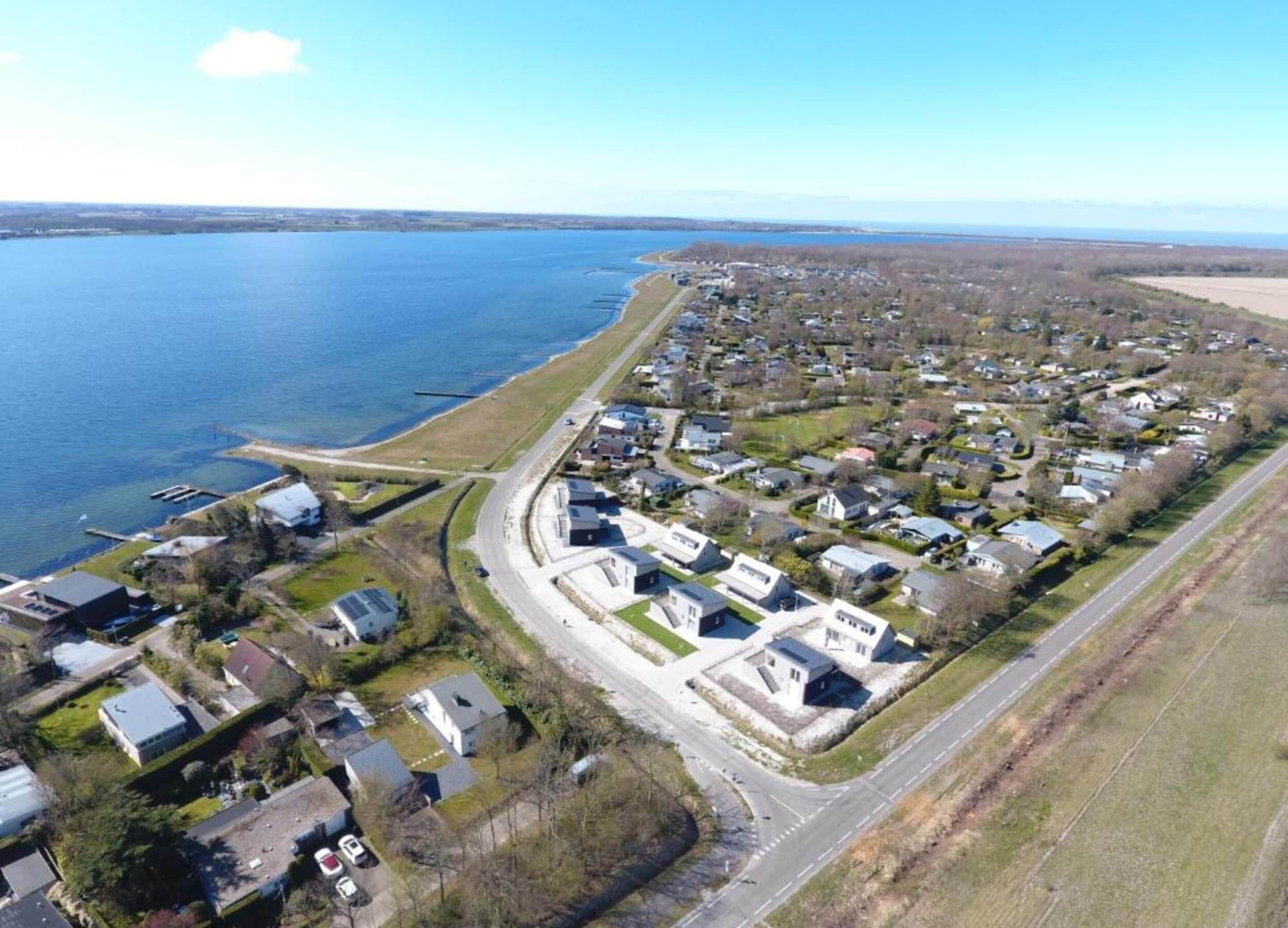 An aerial view of a residential area with houses, a road, and a bridge over a body of water.