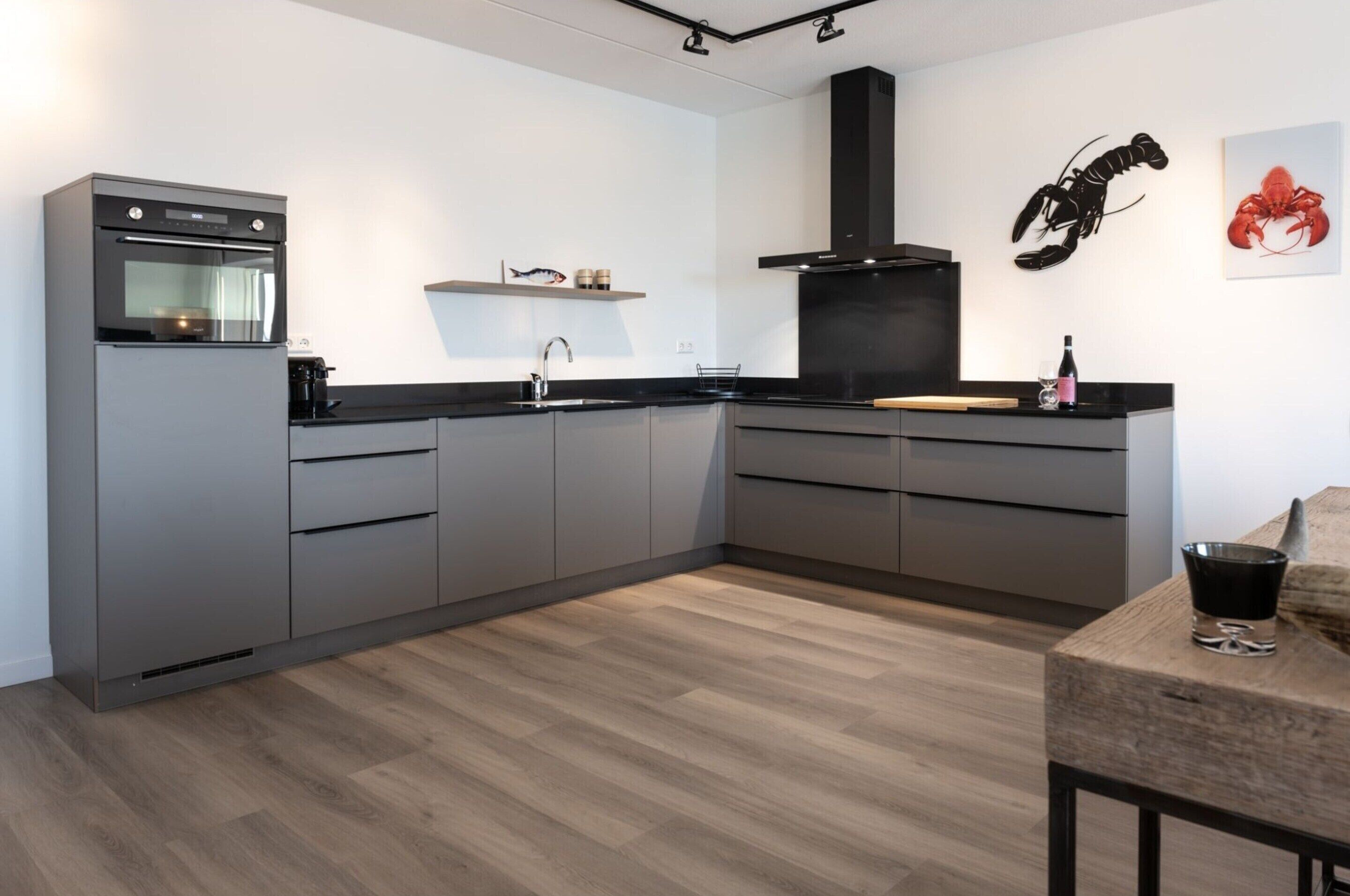 Una cocina moderna con armarios grises, encimera negra y mesa de comedor de madera.