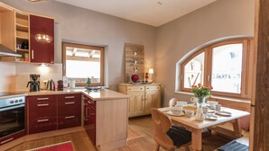 A compact kitchen with wooden cabinets, a central island, and a dining area with a table and chairs. - Unique Chalet in the Center of Elmau Near Skilift (Ellmau)