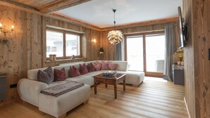A cozy living room with a sectional sofa, wooden floors, and large windows. - Unique Chalet in the Center of Elmau Near Skilift (Ellmau)