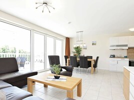 A modern apartment with a dining area, kitchen, and a balcony with outdoor furniture.