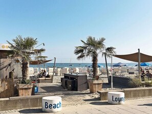 Een strandlounge met zitplaatsen buiten en palmbomen.