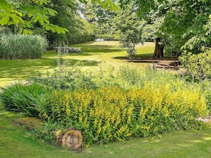 Ein gepflegter Garten mit vielfältigen Pflanzen und einer Bank.
