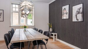A dining area with a wooden table, black chairs, a hanging light fixture, and framed animal pictures on the wall. - 8 Person Holiday Home in Norre Nebel (Norre Nebel)