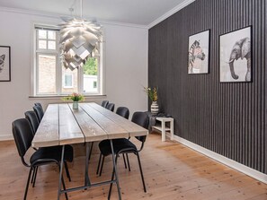A dining area with a wooden table, black chairs, a hanging light fixture, and framed animal pictures on the wall. - 8 Person Holiday Home in Norre Nebel (Norre Nebel)