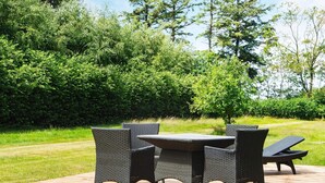 A wooden deck with a round table and four chairs. - 8 Person Holiday Home in Norre Nebel (Norre Nebel)