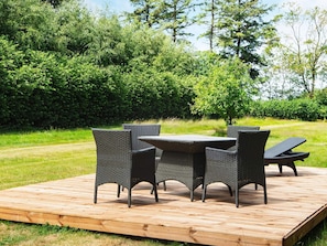 Eine Holzterrasse mit einem runden Tisch und vier Stühlen.