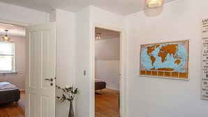 A hallway with a white door, a globe artwork on the wall, and a bed in the adjacent room. - 8 Person Holiday Home in Norre Nebel (Norre Nebel)