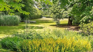 A well-maintained garden with a variety of plants and a bench. - 8 Person Holiday Home in Norre Nebel (Norre Nebel)