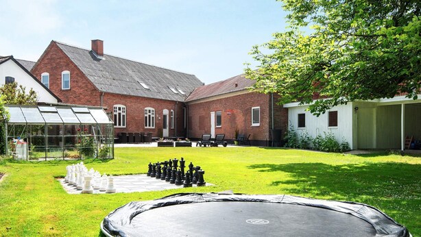 A backyard with a trampoline, a chessboard, and a greenhouse. - 8 Person Holiday Home in Norre Nebel (Norre Nebel)