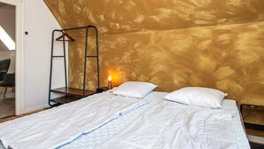 A bedroom with a bed, two pillows, a bedside table, a lamp, and a hanging chair. - 8 Person Holiday Home in Norre Nebel (Norre Nebel)