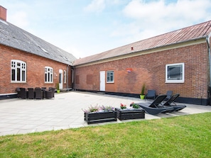 A courtyard with a brick building, outdoor seating, and planters. - 8 Person Holiday Home in Norre Nebel (Norre Nebel)