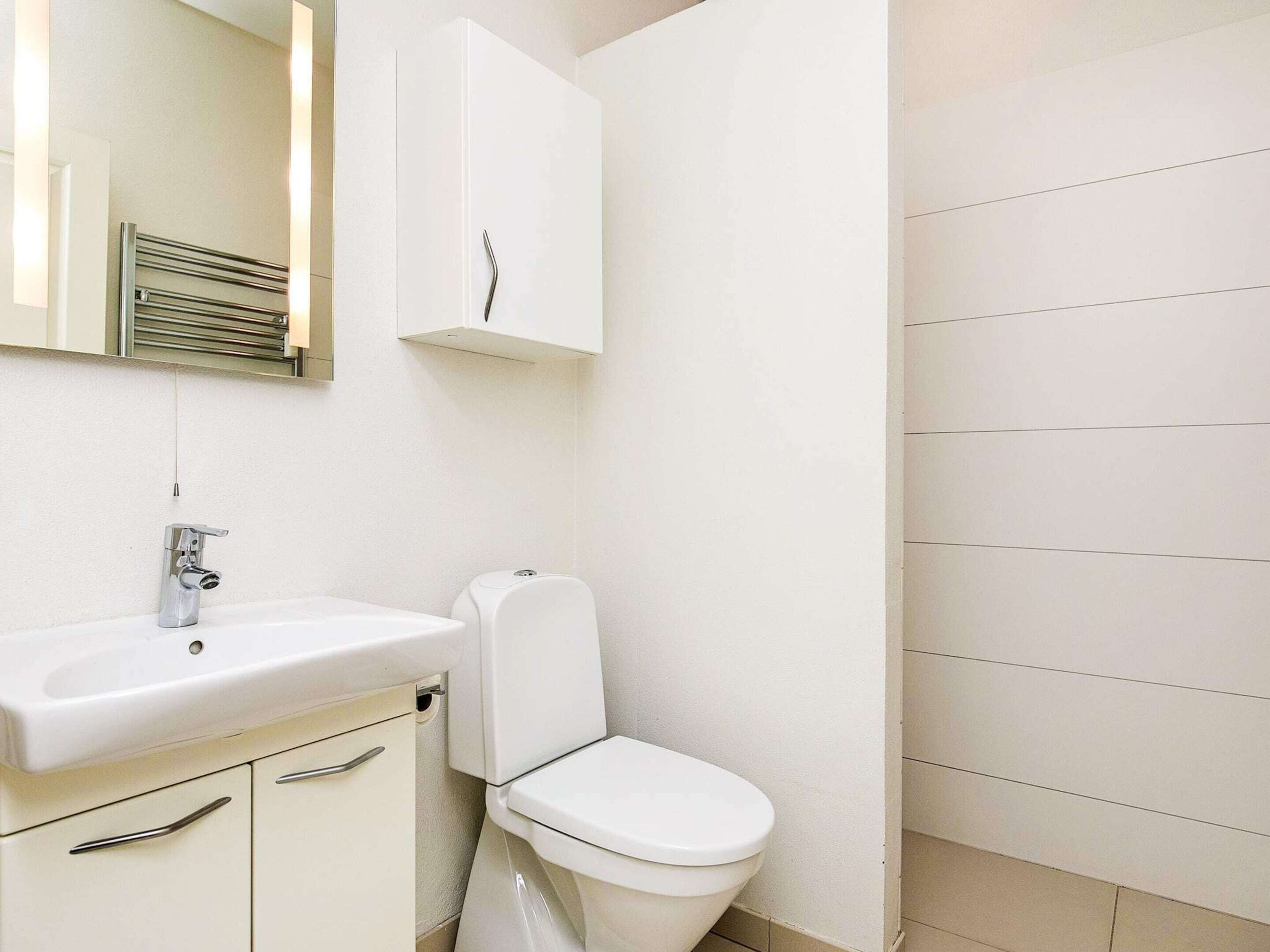 A bathroom with a white sink, a toilet, and a cabinet with drawers.